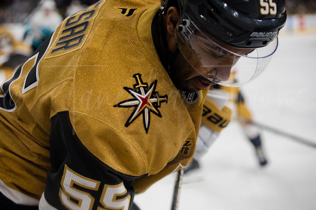 NHL hockey player in gold Vegas Golden Knights jersey number 55 skates on ice during game action.