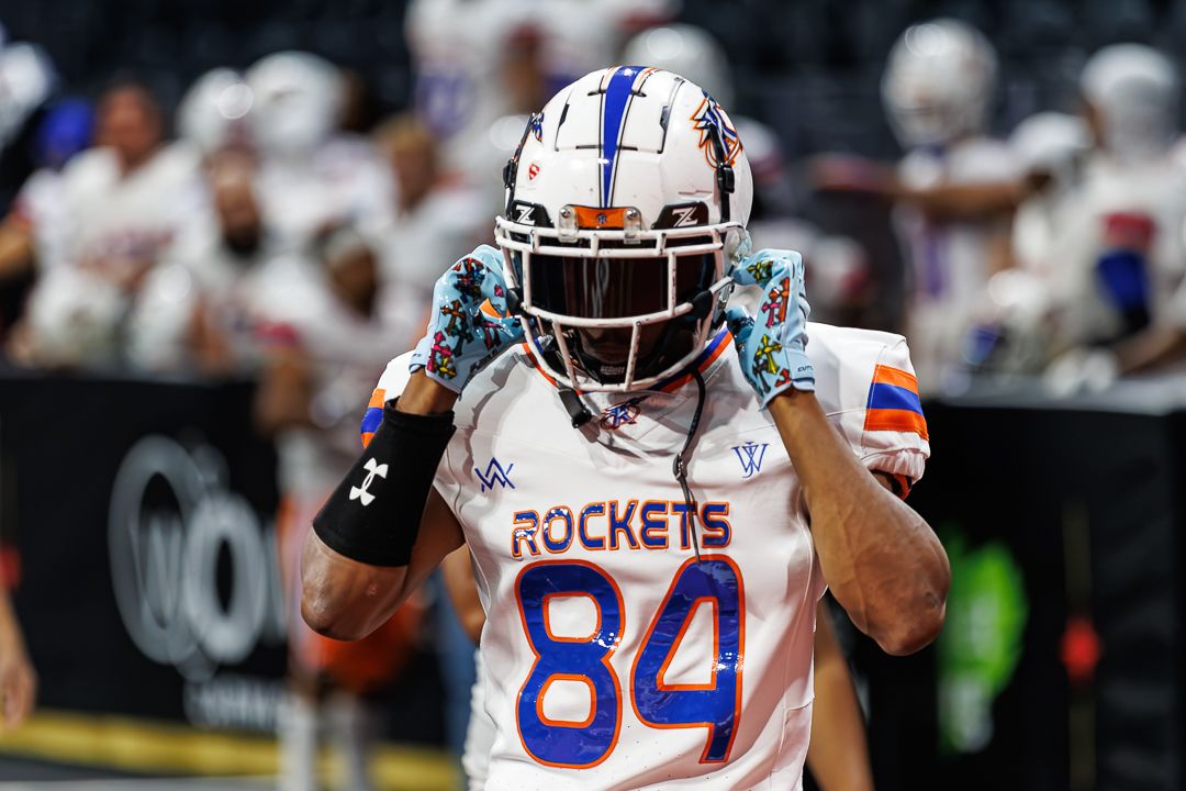 Arena football player wearing number 84 Rockets jersey celebrates on the field.