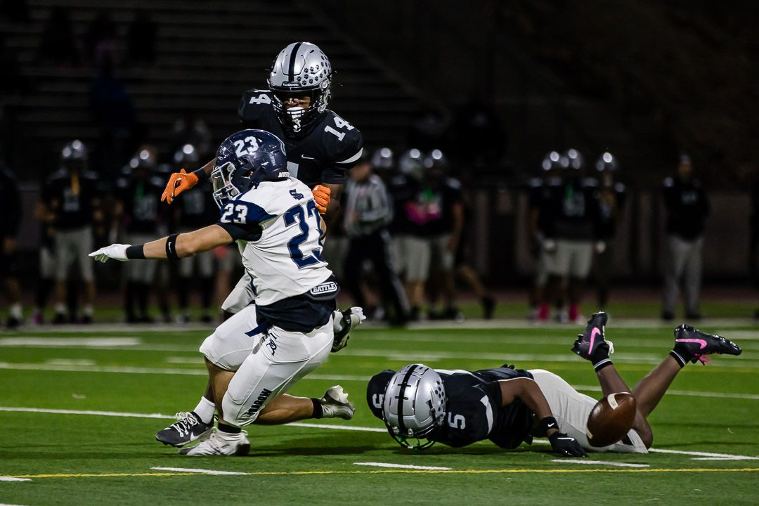 Football players dive and tackle during a crucial defensive play on the field.