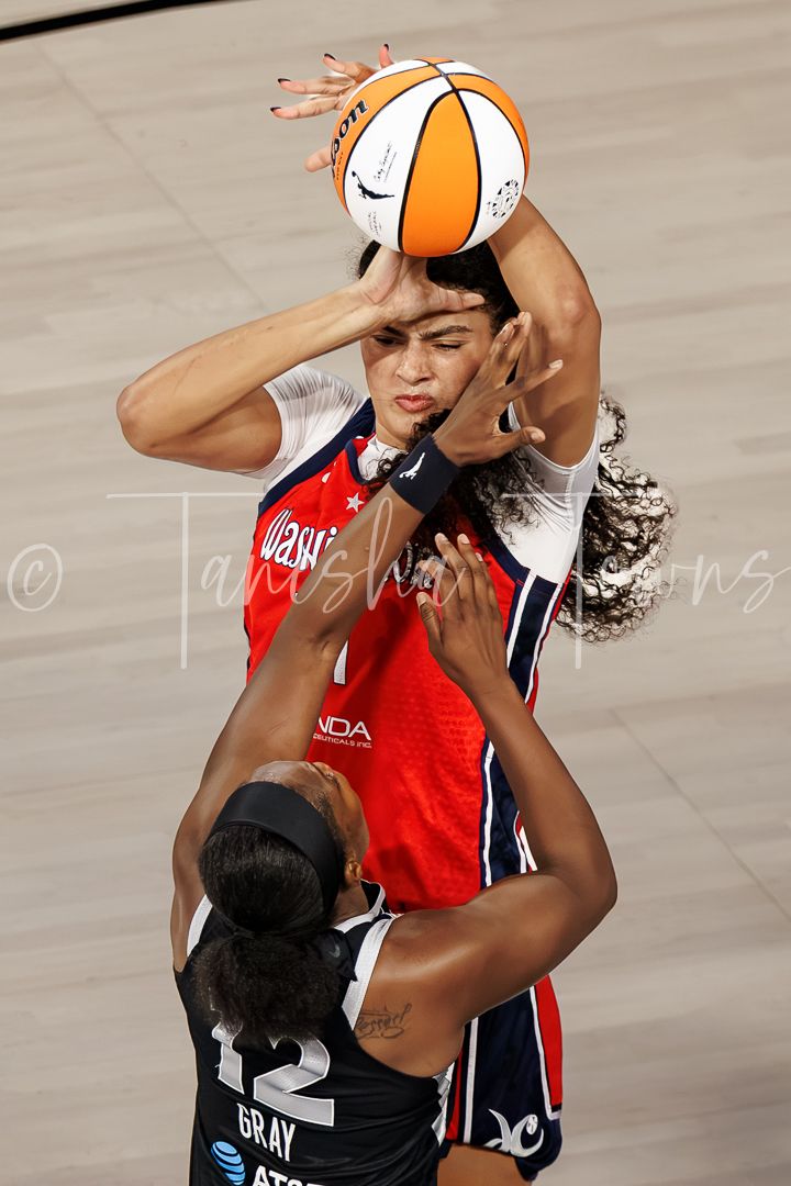 A Washington Mystics player shoots over Chelsea Gray #12 of the Las Vegas Aces in a WNBA game.