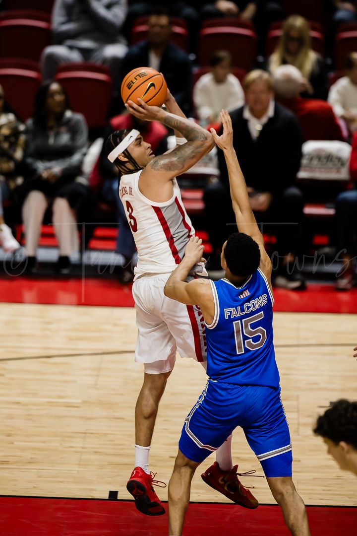 Basketball player in white jersey attempts a jump shot while being defended by player in blue jersey number 15.