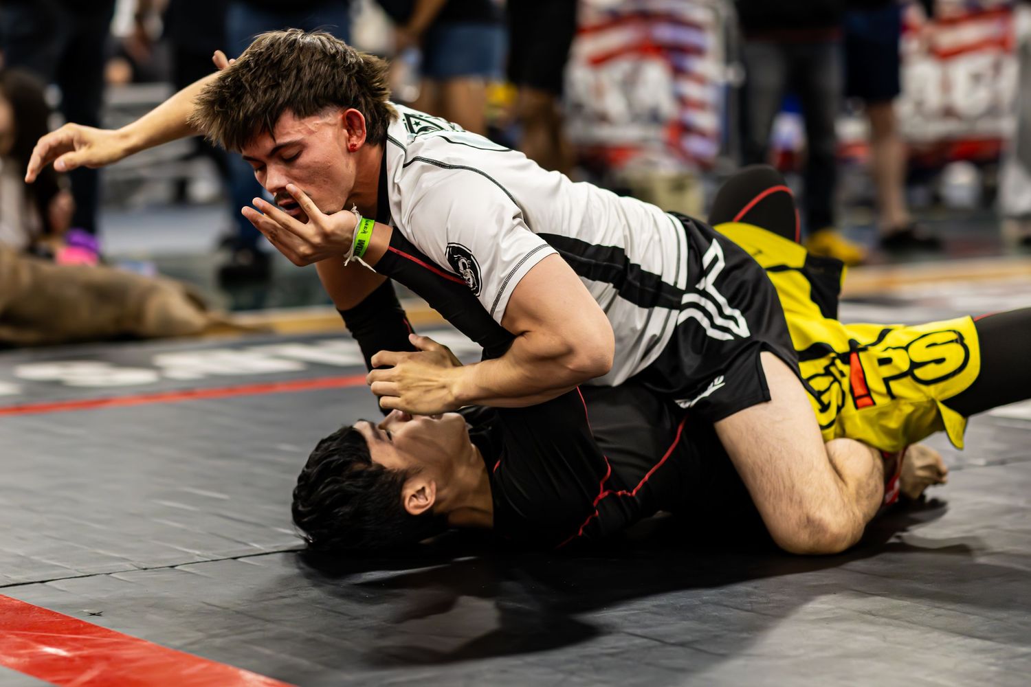 Two wrestlers compete on a mat, with one athlete pinning the other down during an intense grappling match.