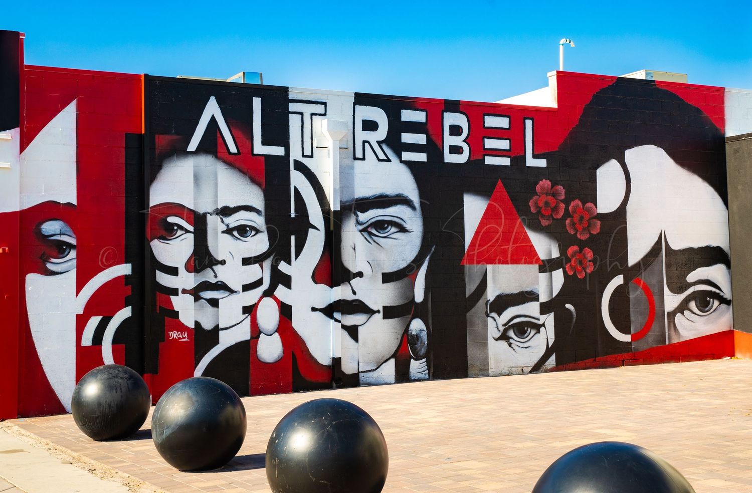 Black and red street art mural with text 'The Rebel' and decorative elements.