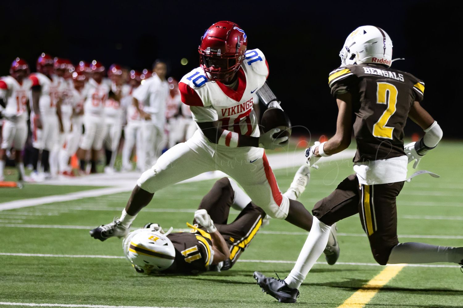 Football players engage in a dramatic tackle during a night game.
