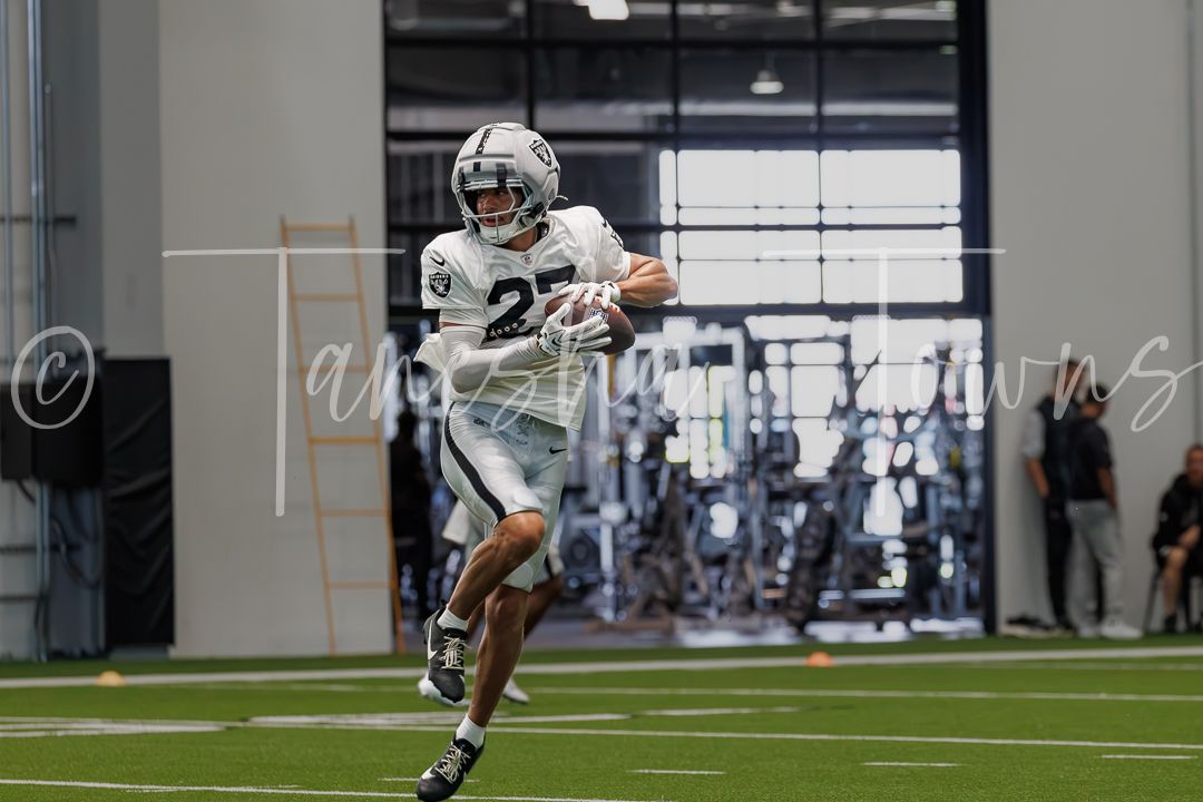 Football player wearing number 22 catches a pass during an indoor practice session at a modern training facility.