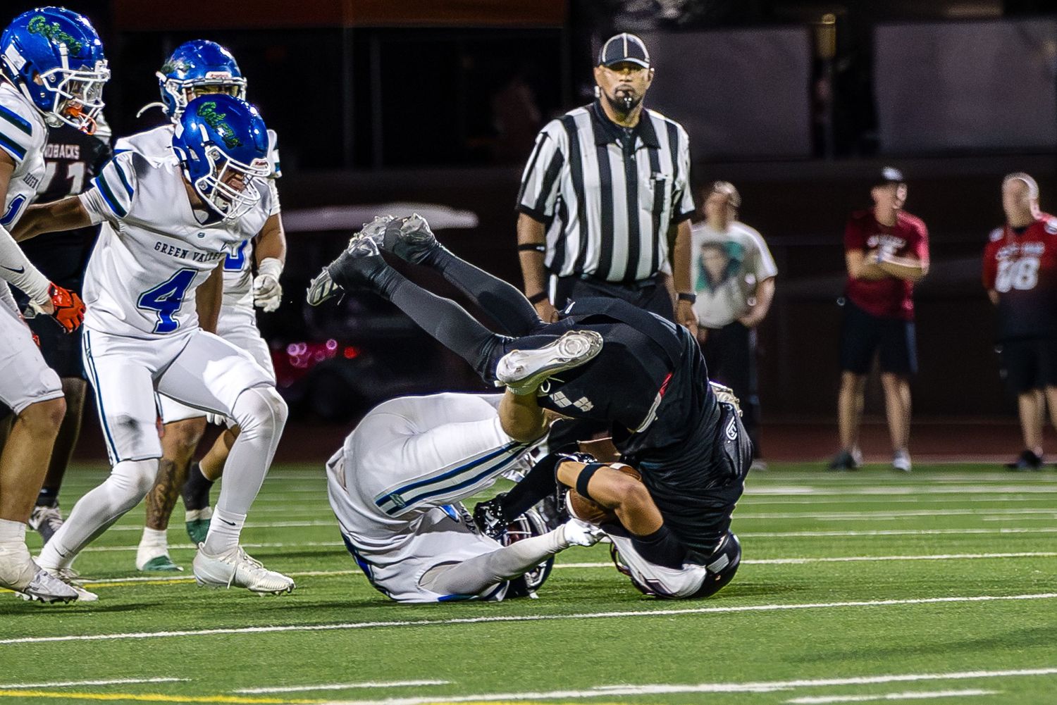 Football players in action during a nighttime game on artificial turf.