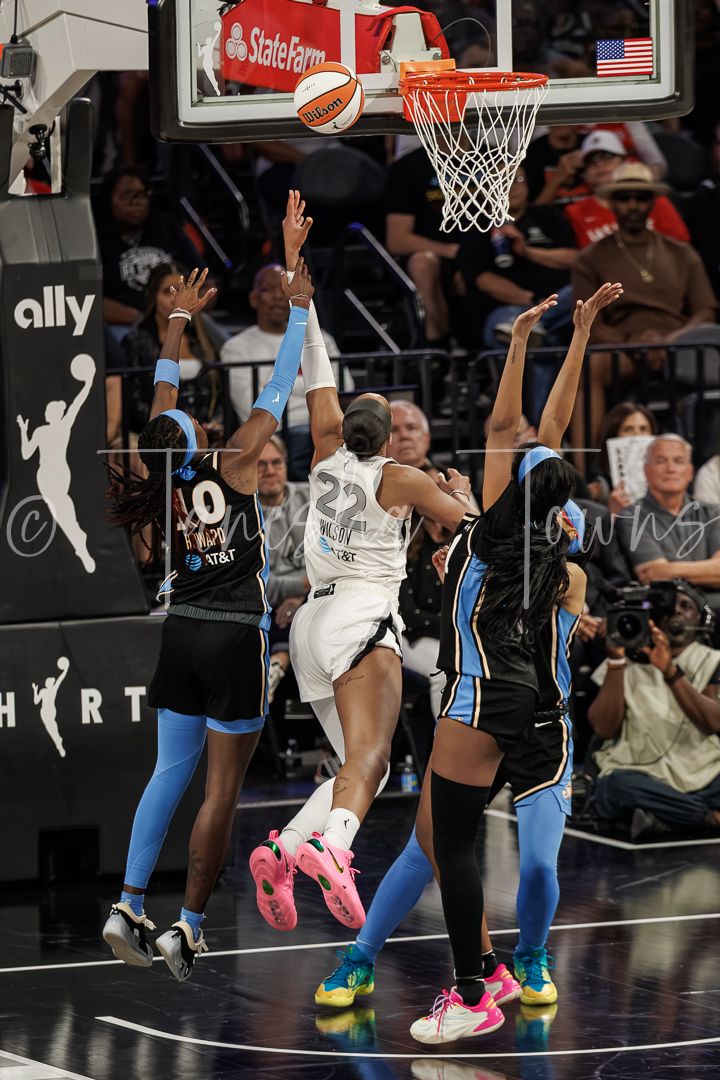 WNBA player #22 drives to the basket against Chicago Sky defenders during an intense game action shot.