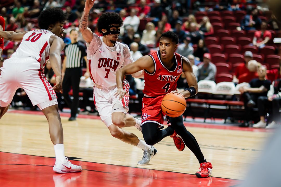 Basketball players compete for possession during an intense college basketball game on the court.