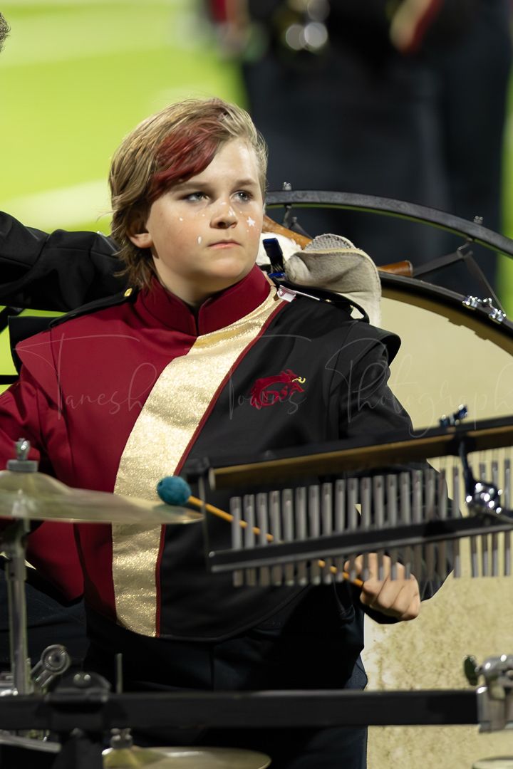 Marching band member plays xylophone during nighttime field performance.