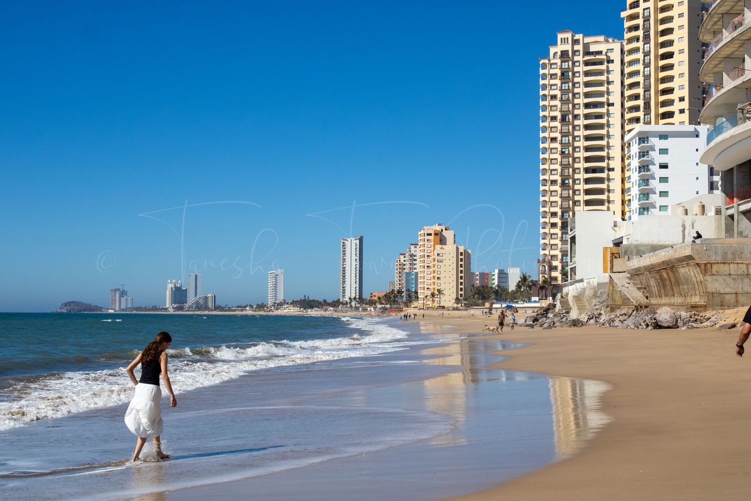 Sandy beach with high-rise buildings and ocean views along the coastline.