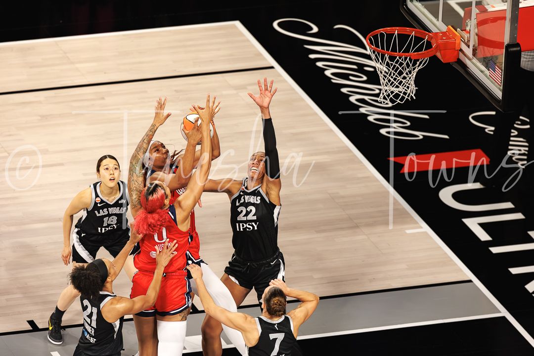 Multiple players battle for a rebound during an intense WNBA game featuring the Las Vegas Aces.