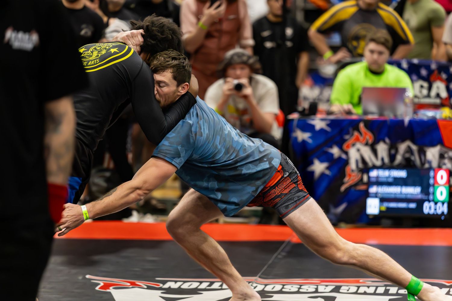 Competitive bowler in blue shirt makes a dramatic delivery shot at a professional bowling tournament on a red lane.