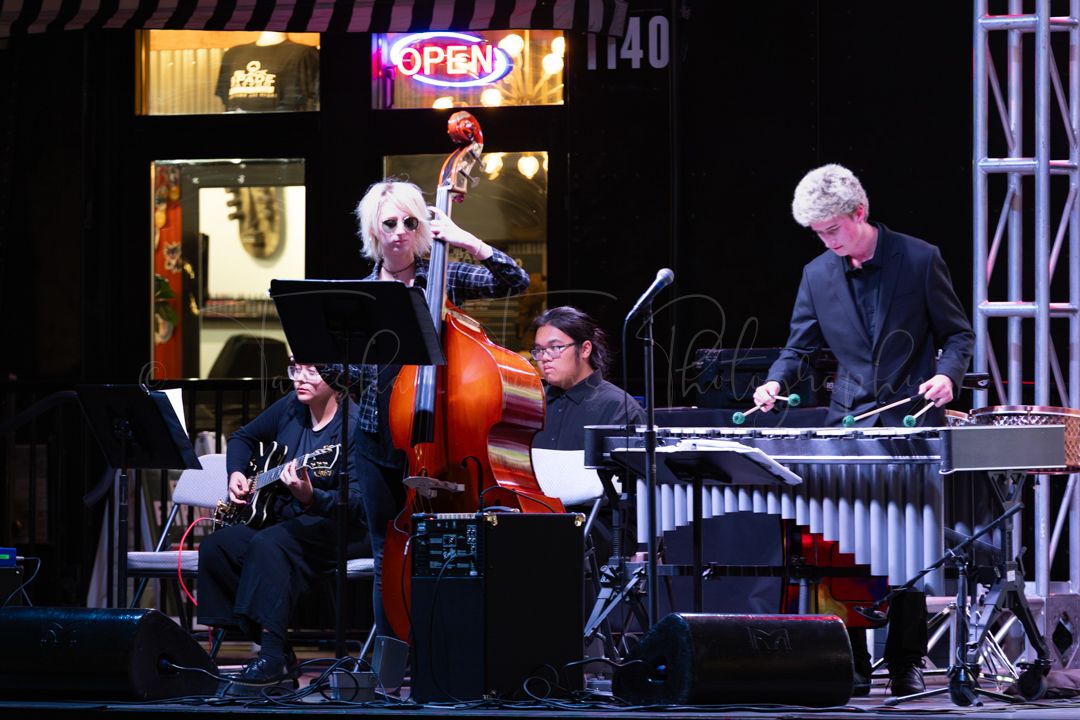 Dark stage setup with musical equipment and lighting rigs visible during a jazz performance.