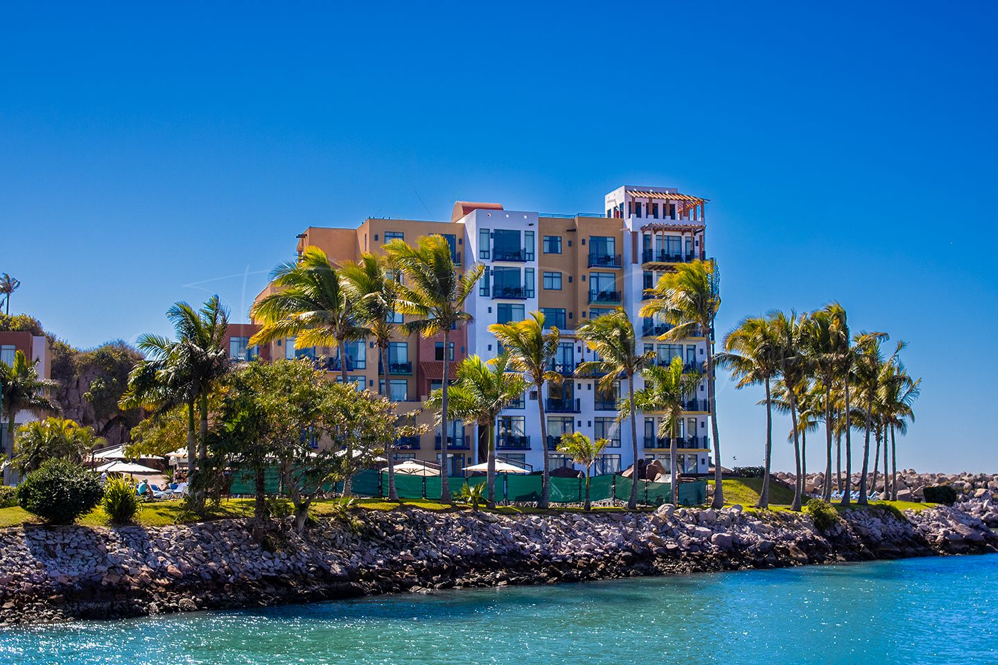 Waterfront homes with palm trees along blue tropical waters.