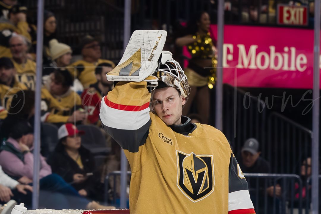 NHL goalie makes a save in goal while wearing a Vegas Golden Knights jersey during a hockey game.