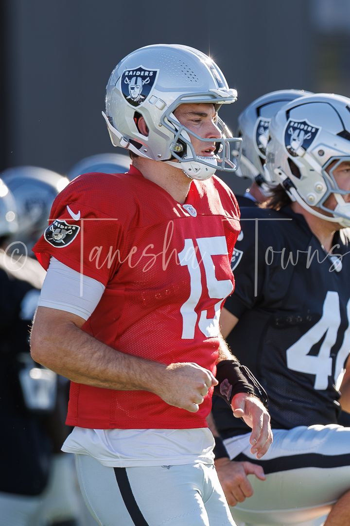 Raiders player #15 in red jersey and silver helmet jogs during NFL practice session.