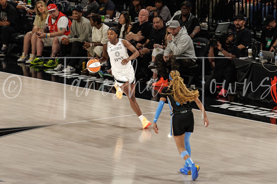WNBA players compete on the court during a professional basketball game, with one player passing the ball.