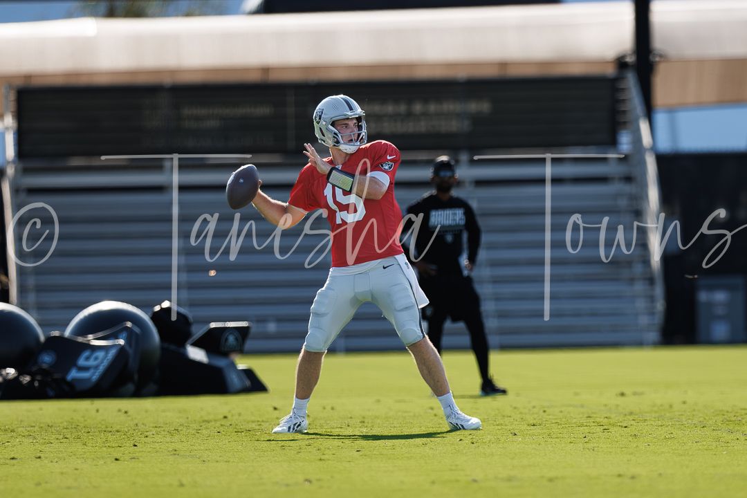 NFL quarterback in red jersey throws pass during outdoor practice session.