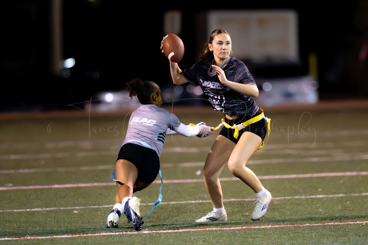 Two players battle for the ball during an intense flag football match.