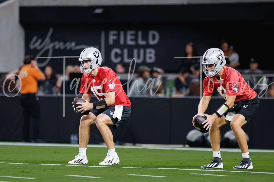 Two Las Vegas Raiders quarterbacks practice snap exchanges during warmups at Allegiant Stadium's Wynn Field Club.