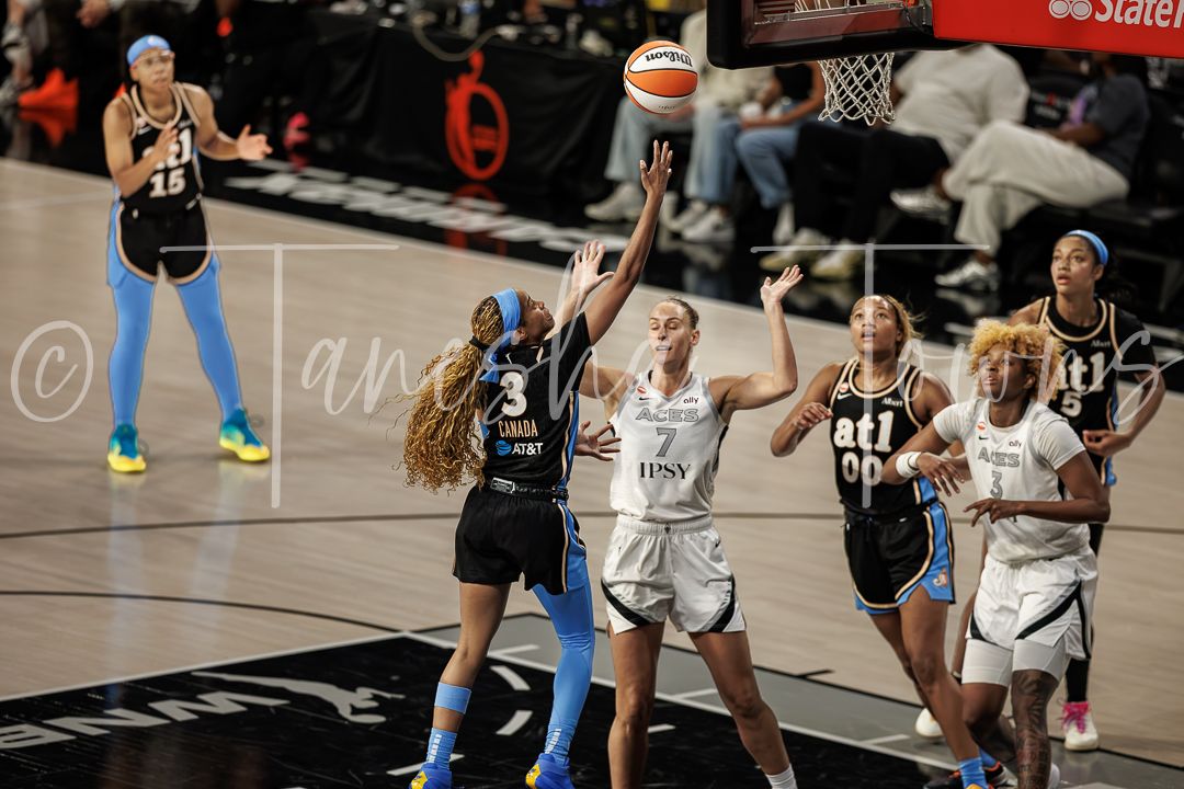 WNBA players compete for a rebound during an intense basketball game, with number 3 attempting a shot near the basket.
