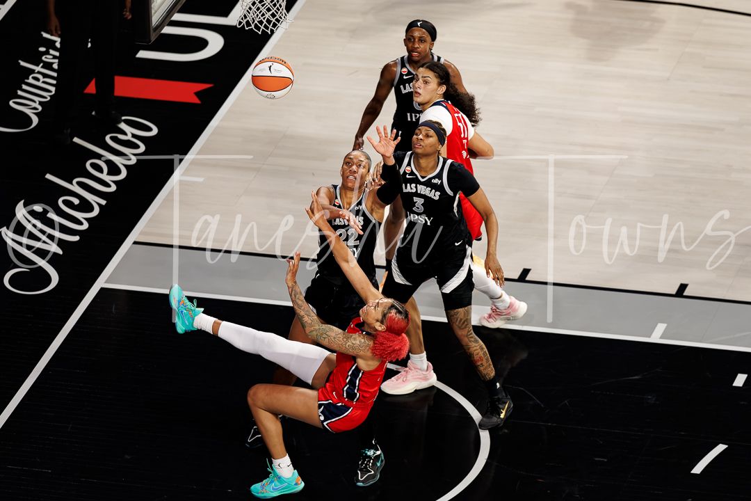 WNBA player falls to the court while attempting a shot during a competitive game.