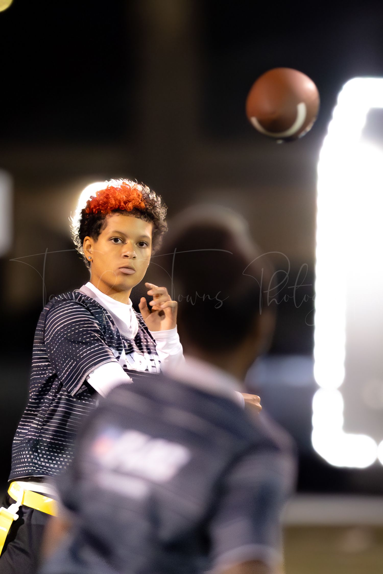 A football player practices throwing drills during a nighttime training session.