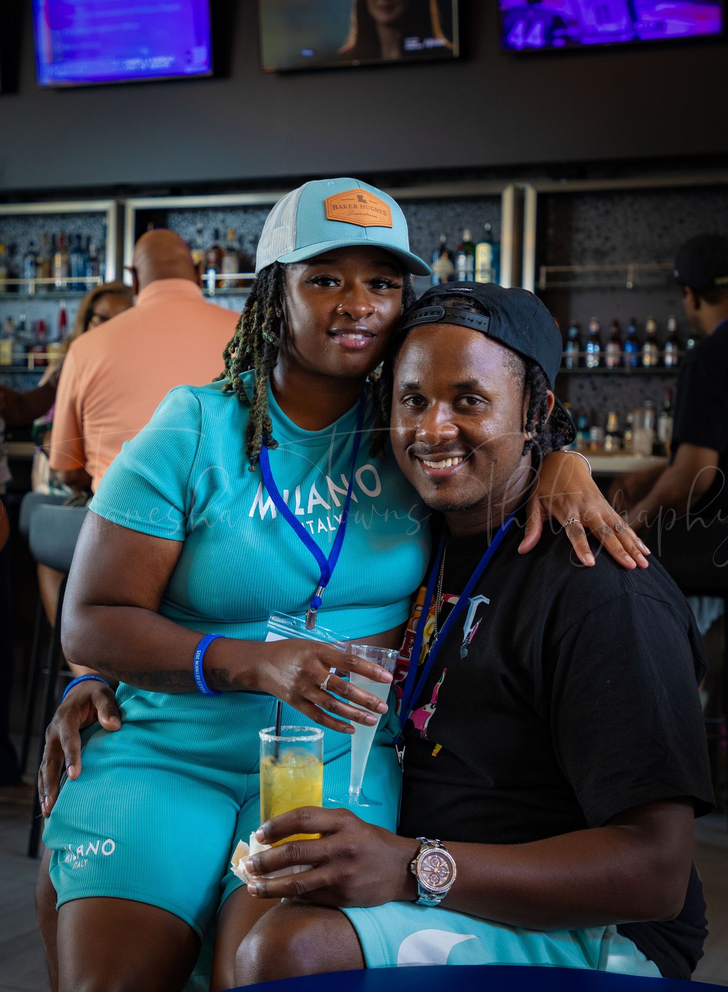 Two people enjoying drinks and conversation at a bar with blue lighting in the background.
