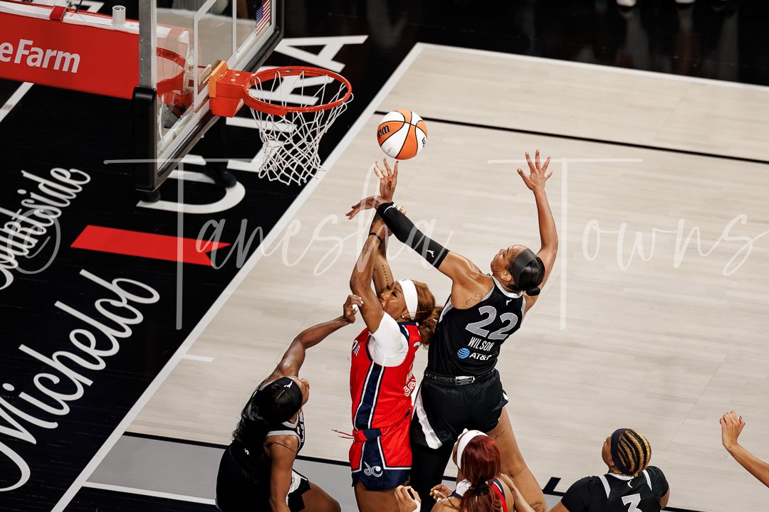 WNBA players battle for a rebound under the basket during an intense professional game.