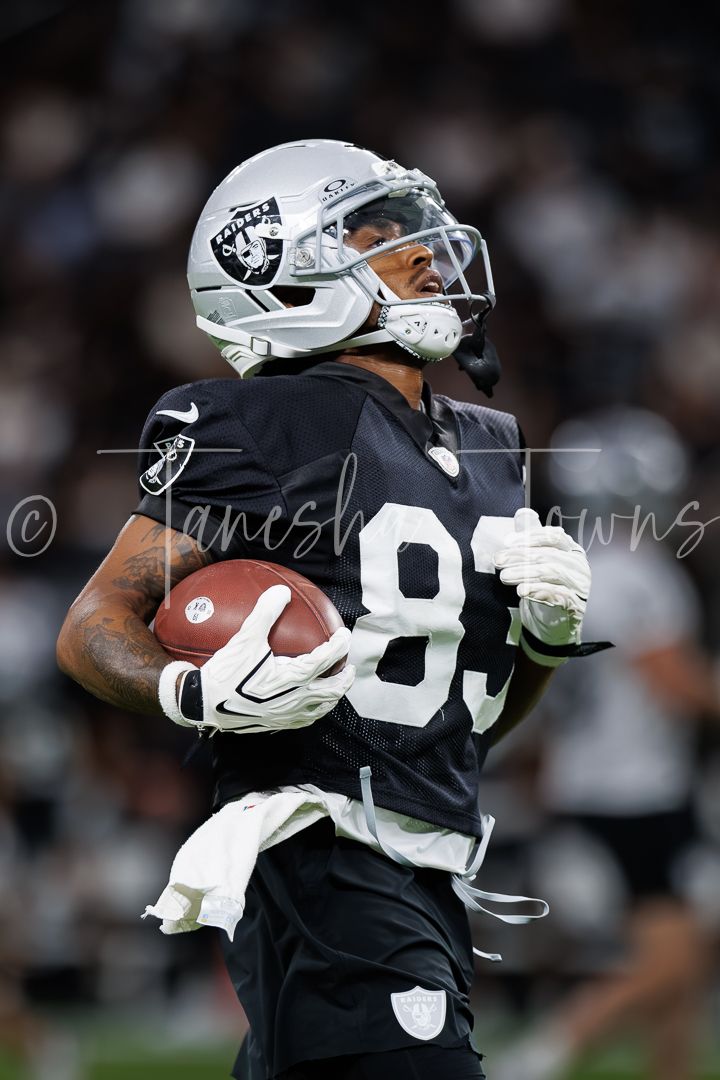 Las Vegas Raiders player #83 in black uniform catches football during NFL game action.