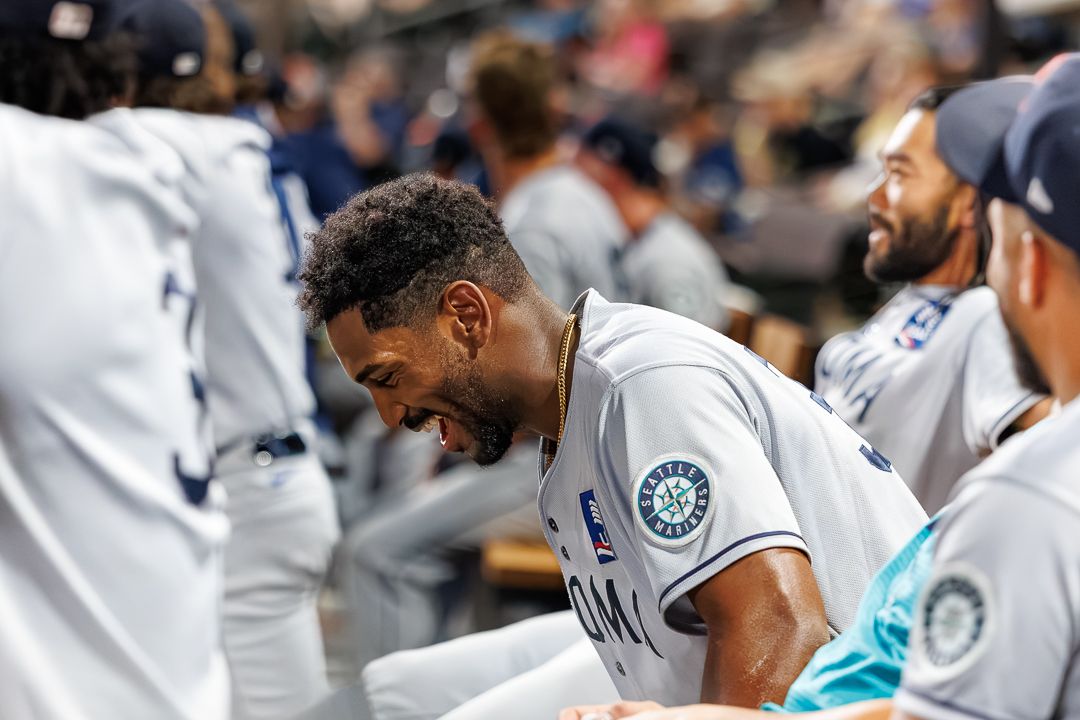 Seattle Mariners player laughing in dugout with teammates during MLB baseball game.
