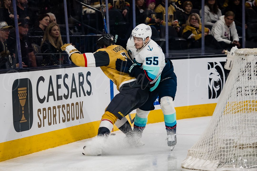 NHL hockey players battle for the puck along the boards during an intense game between the Sharks and Bruins.