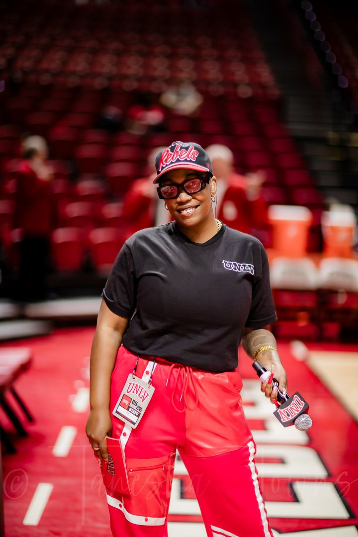 Dance team members in black shirts and red pants perform during a basketball game.