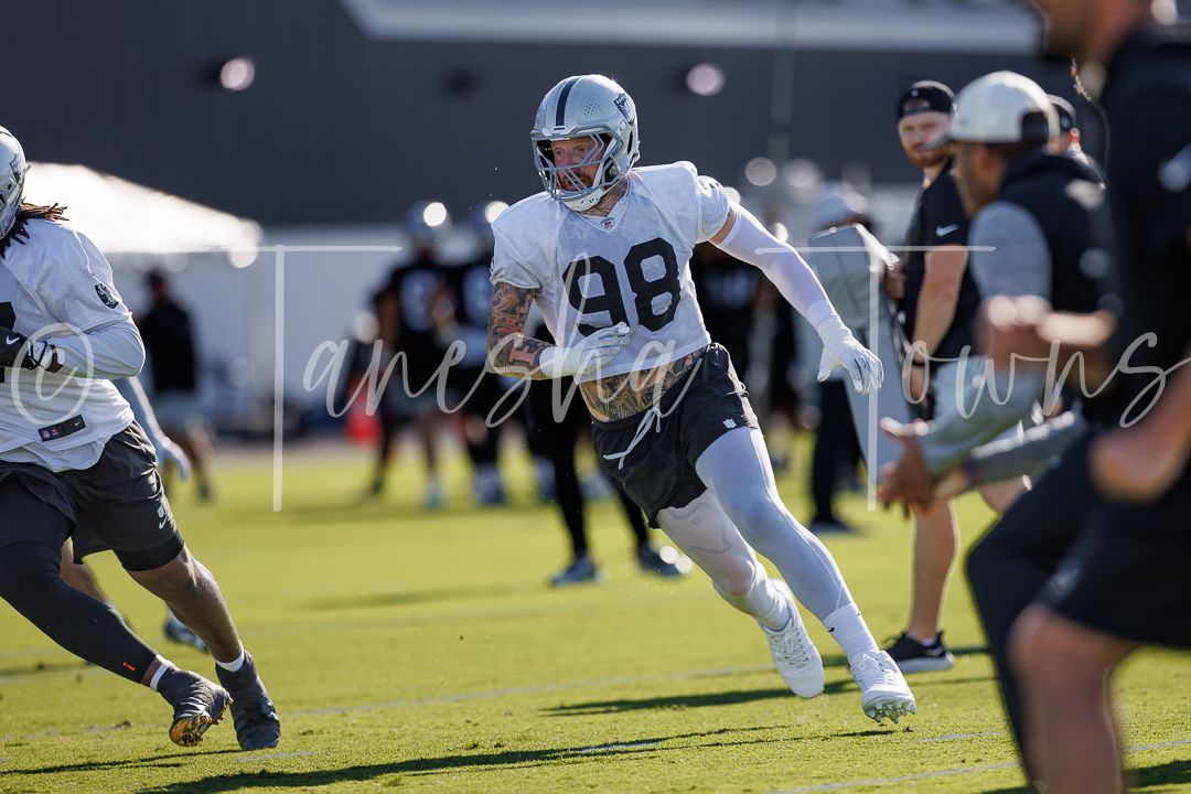 Las Vegas Raiders player number 98 runs a defensive drill during outdoor NFL training camp practice.