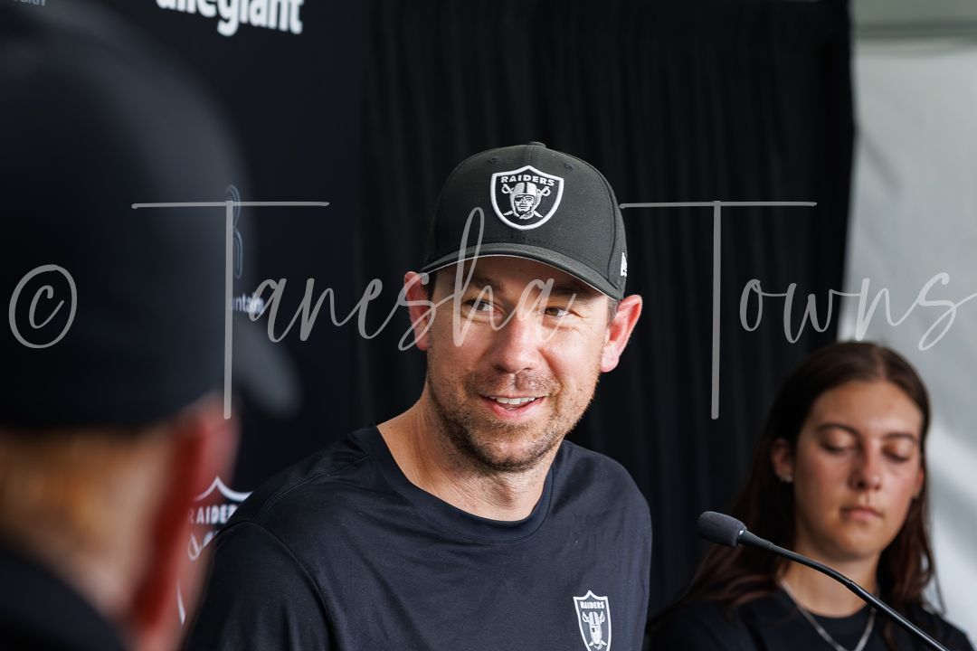 Man in Raiders cap speaks at NFL press conference with microphone nearby.