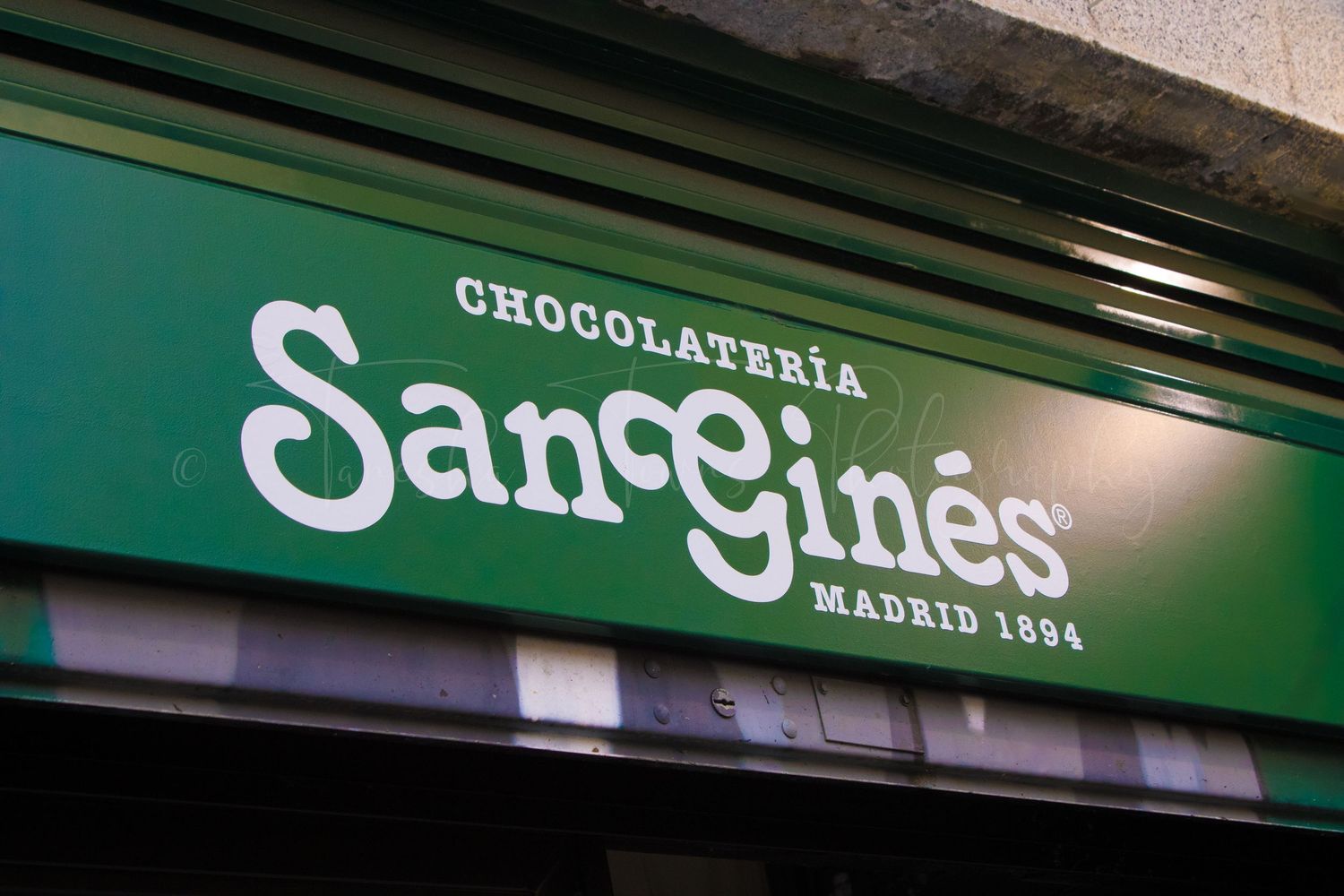Storefront signs for a chocolate shop and other businesses in an urban setting.