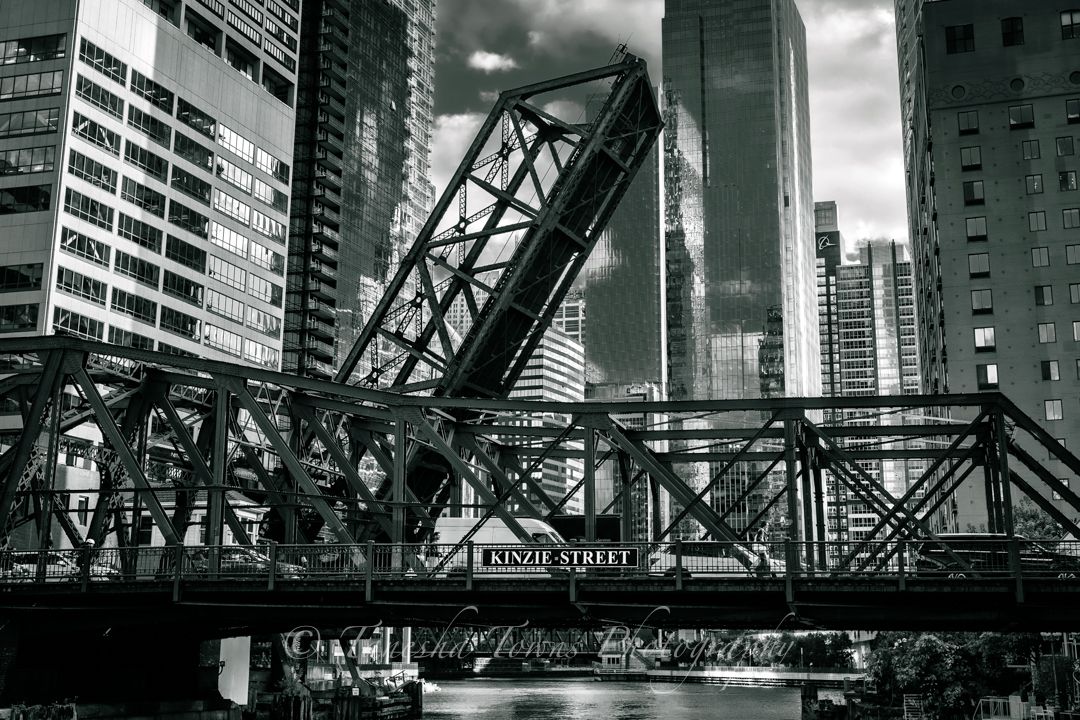 Black and white cityscape with multiple bridges and skyscrapers along Chicago River reflecting urban architecture.