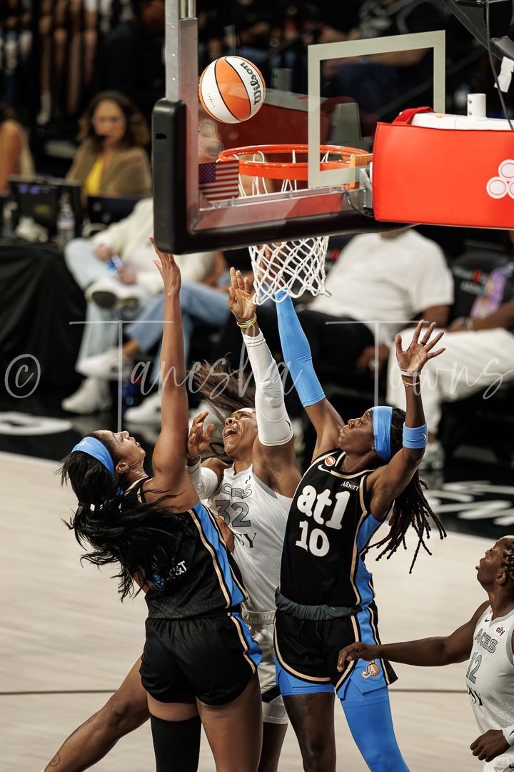 WNBA players leap for a rebound near the basket during a competitive game, with Atlanta Dream number 10 visible.