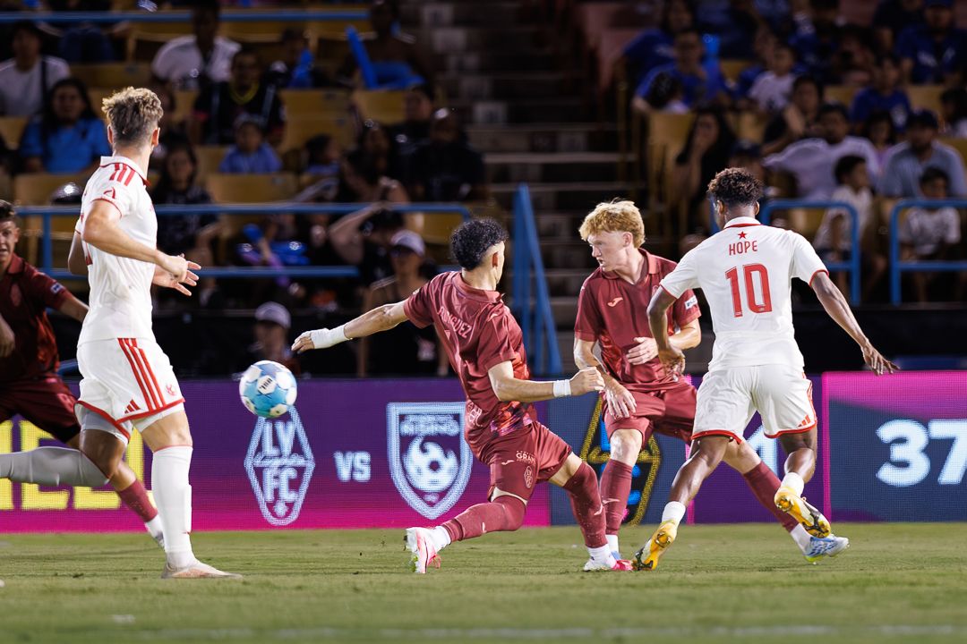 Soccer players compete for the ball during an intense night match at LV FC stadium, player 10 visible.