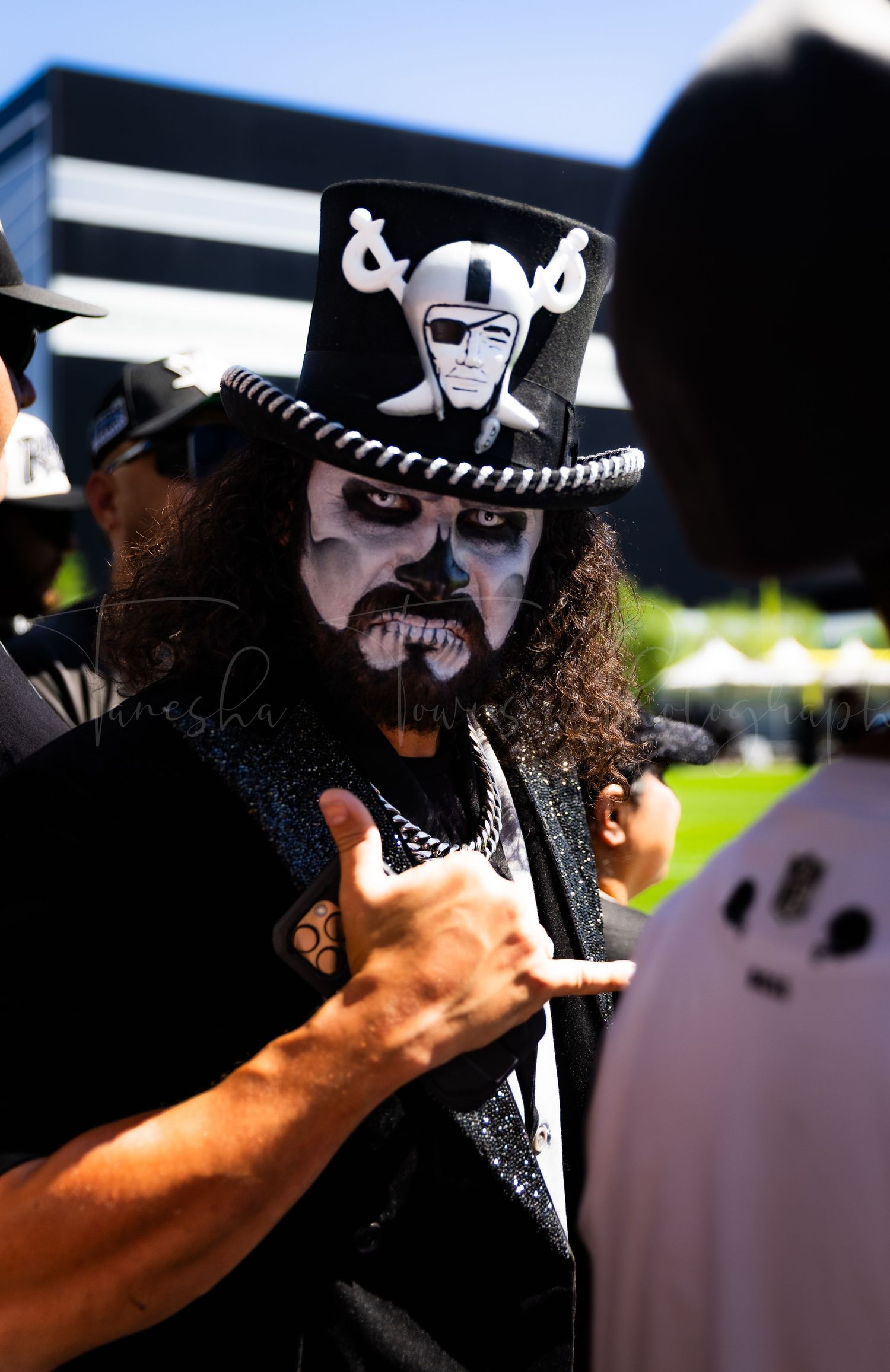 Person wearing black and white face paint and hat in dramatic lighting.