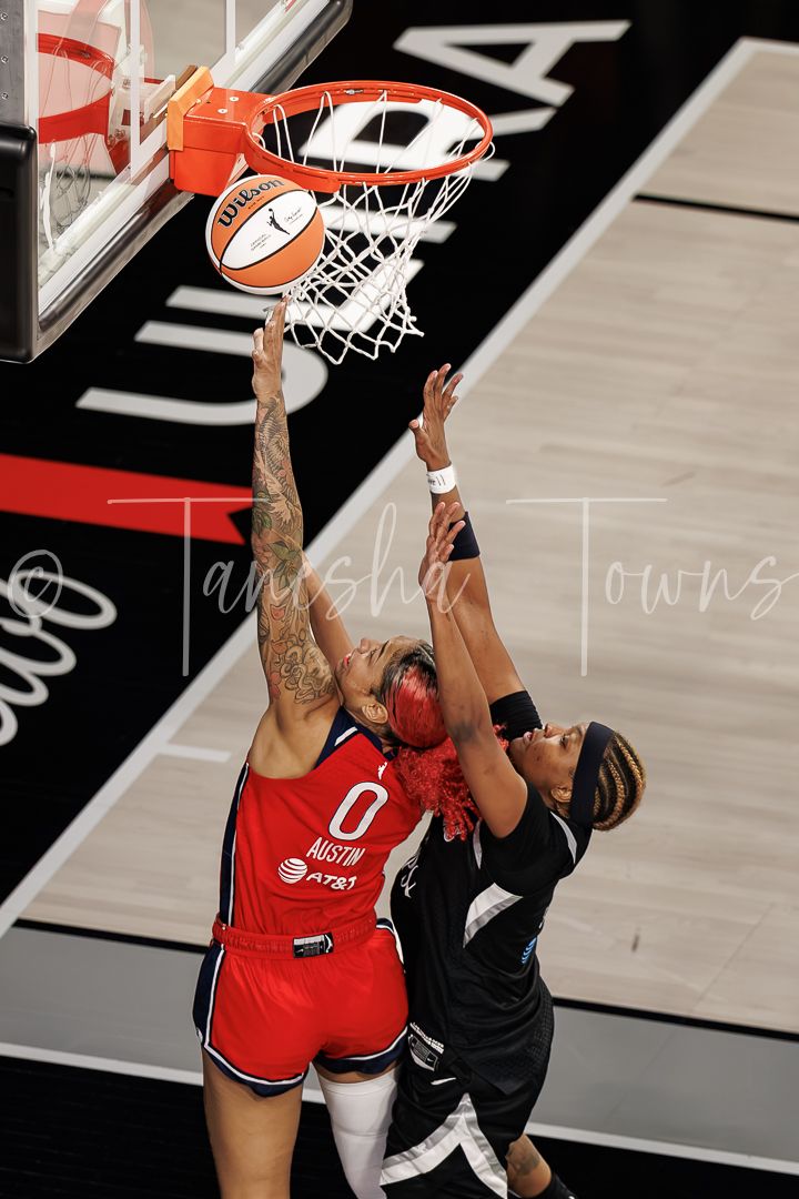 WNBA player #0 from Austin attempts a layup while being defended during a professional basketball game.