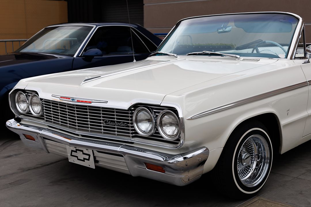 White 1964 Chevrolet Impala convertible classic car parked, featuring dual headlights and chrome grille.