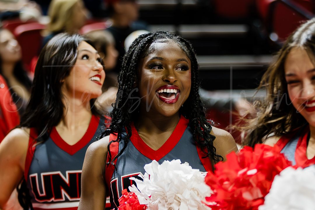 Cheerleaders in red and navy uniforms share a joyful moment during performance.