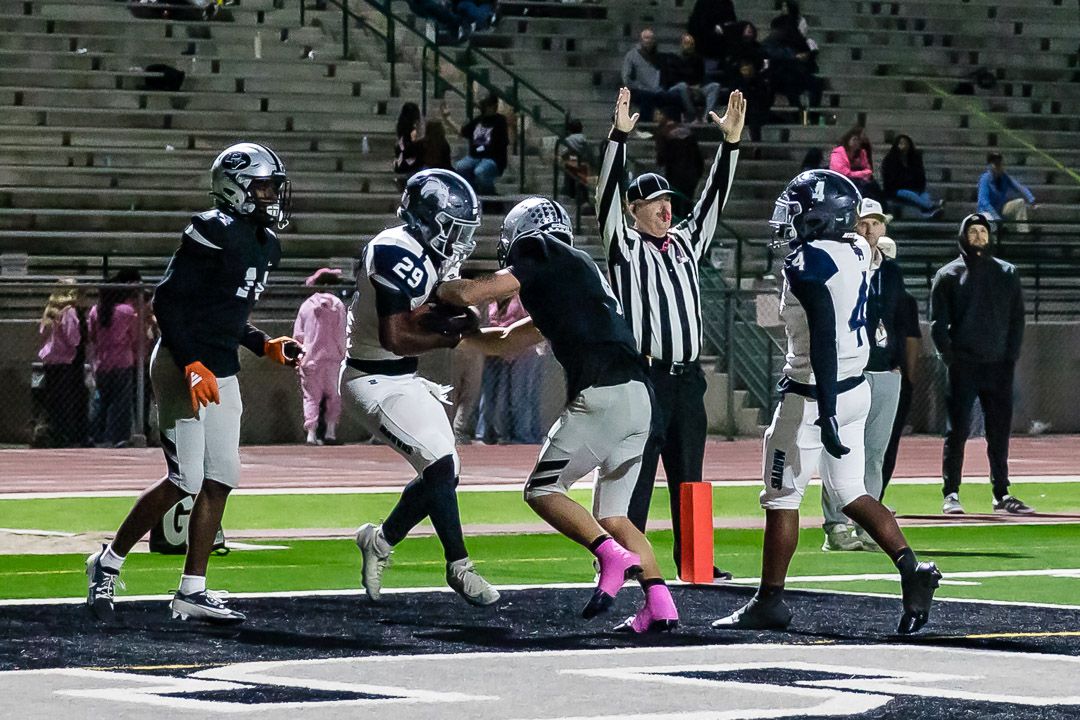 Football players in white and dark uniforms compete during a game on the field.