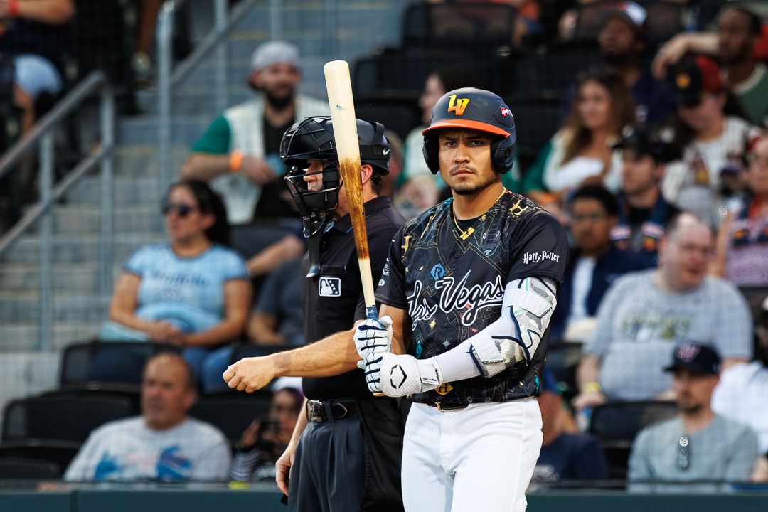Las Vegas Aviators batter stands ready at plate with umpire behind him during professional baseball game.