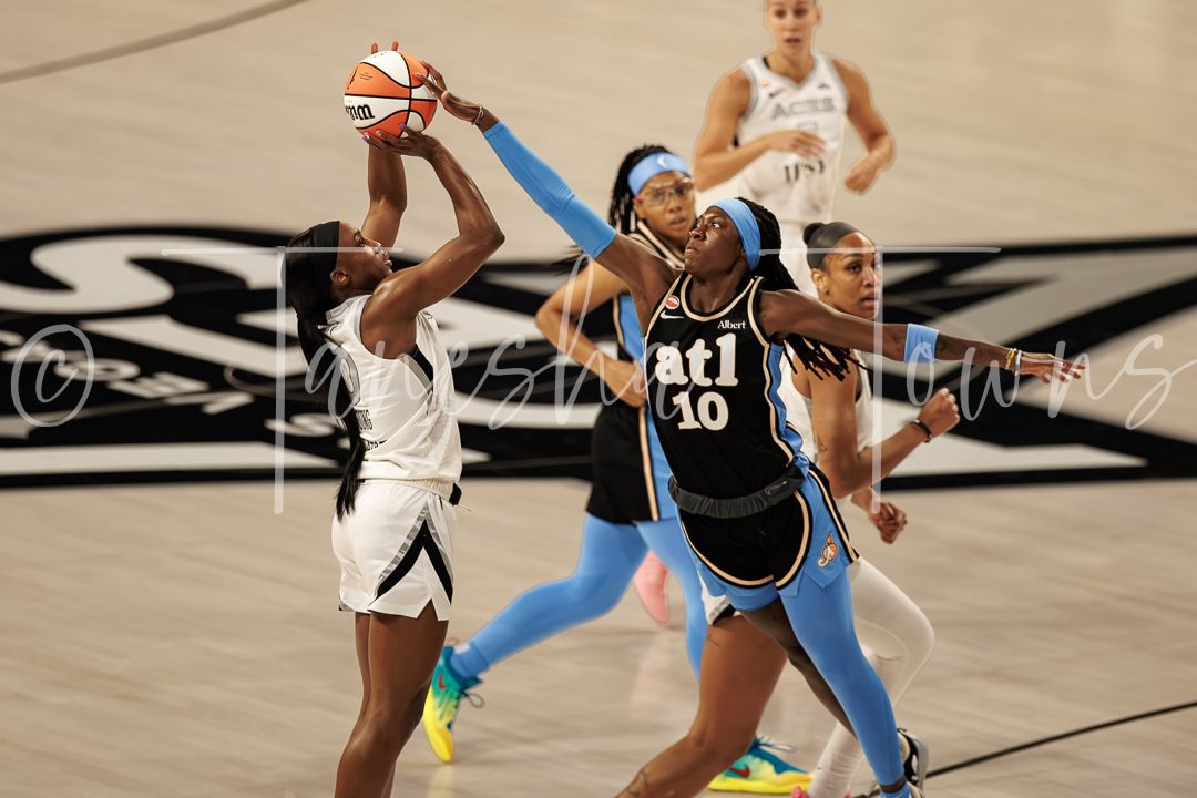 WNBA players compete for the ball during a game, with Atlanta Dream player #10 defending against a shot.