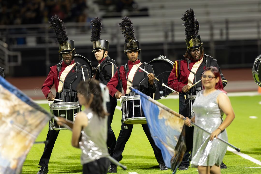 Color guard members performing with flags during marching band show.