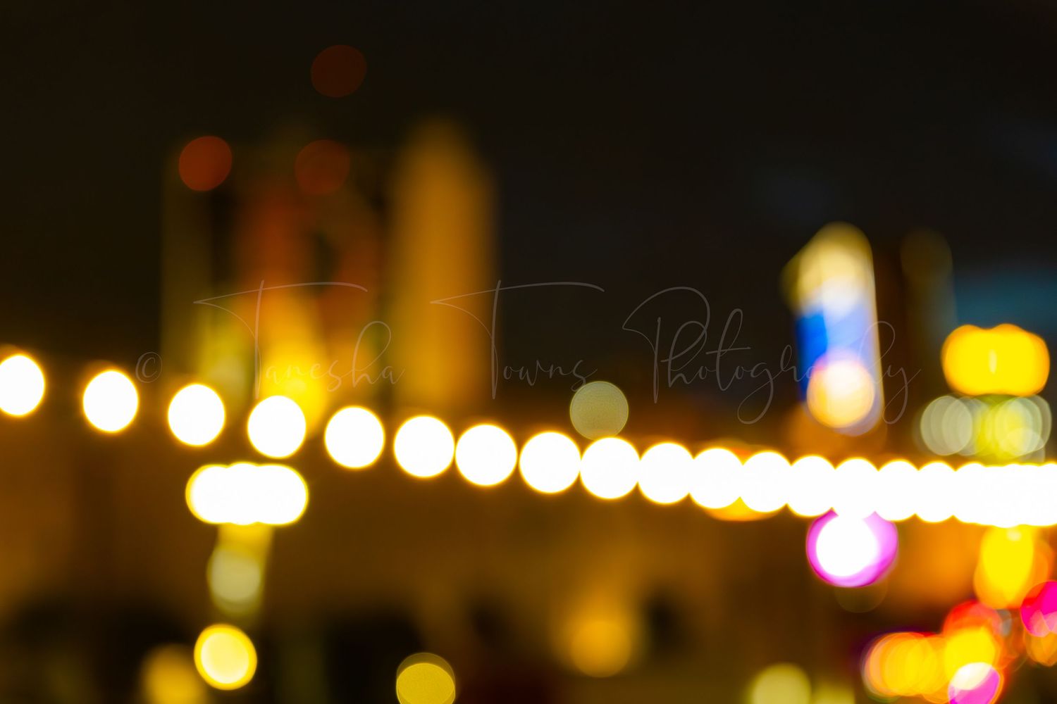 Nighttime cityscape with glowing string lights creating a warm bokeh effect.