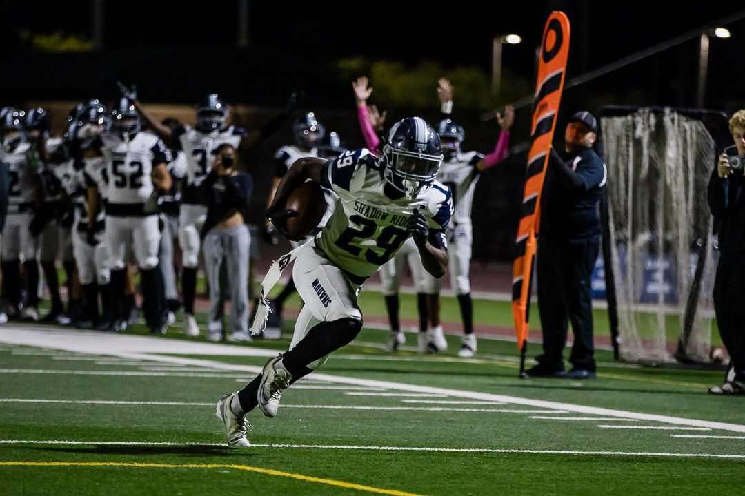Football action shot with orange markers visible on sideline during night game.