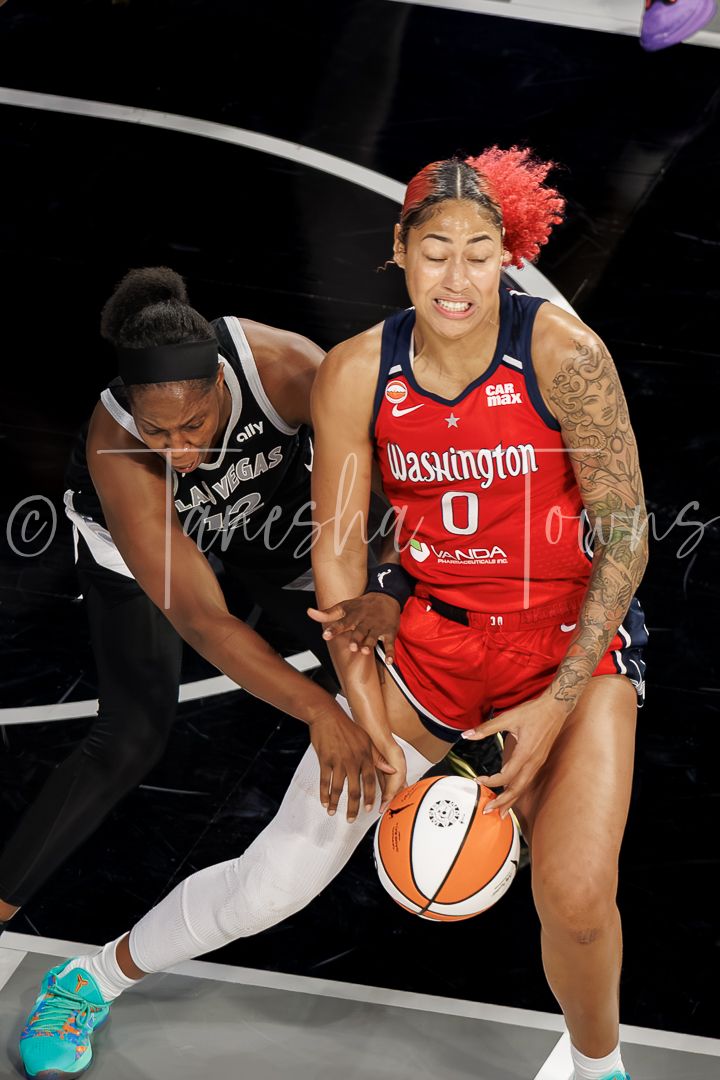 Washington Mystics player #0 battles for the ball against a Las Vegas Aces defender in a WNBA game.